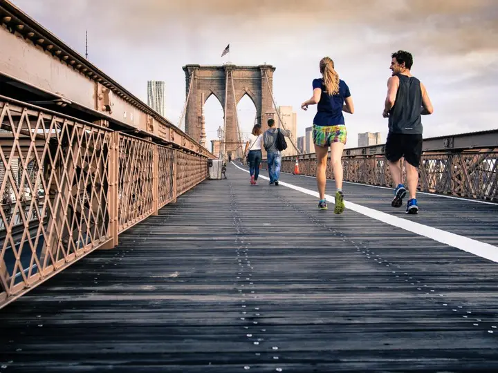 Two runners crossing a bridge in the city
